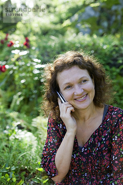 Lächelnde reife Frau  die über ein Mobiltelefon spricht