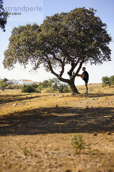 Mann streckt sich gegen einen Baum  Algarve  Portugal