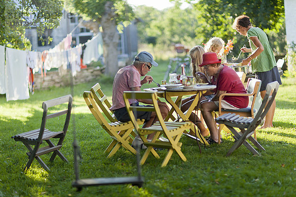 Familienessen am Tisch im Freien im Garten