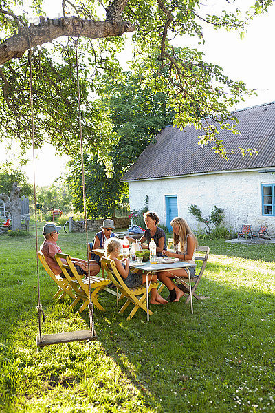 Familienessen am Tisch im Freien im Garten