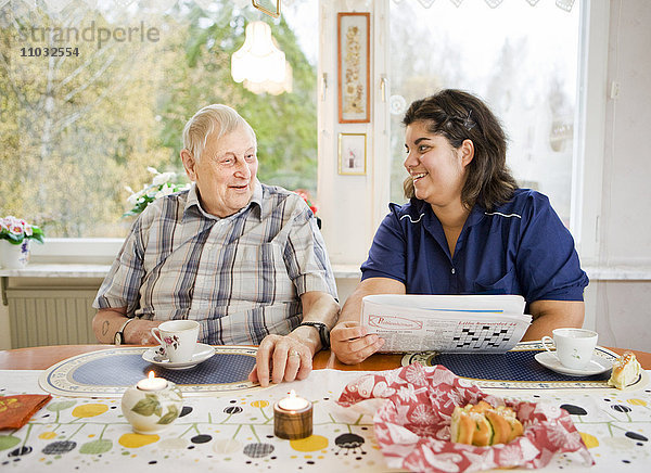 Krankenschwester mit älterem Mann am Tisch  Schweden