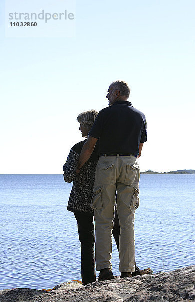 Ein älteres Ehepaar blickt auf das Meer.