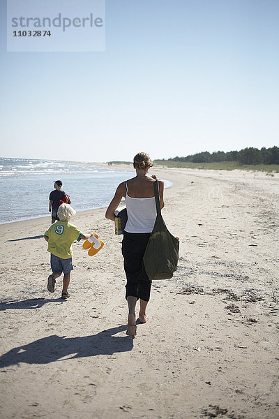 Eine Frau und Kinder am Strand.