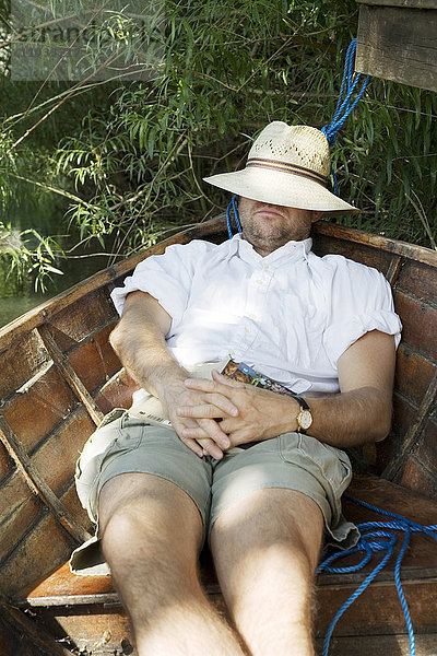 Ein Mann schläft in einem Boot.