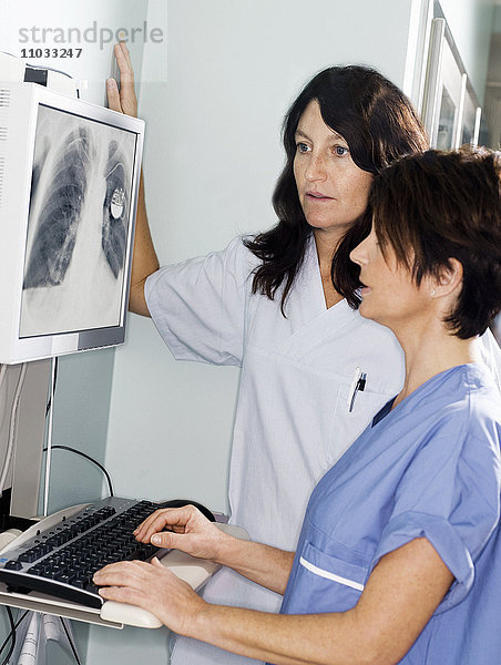 Ein Arzt und eine Krankenschwester sehen sich ein Röntgenbild an.