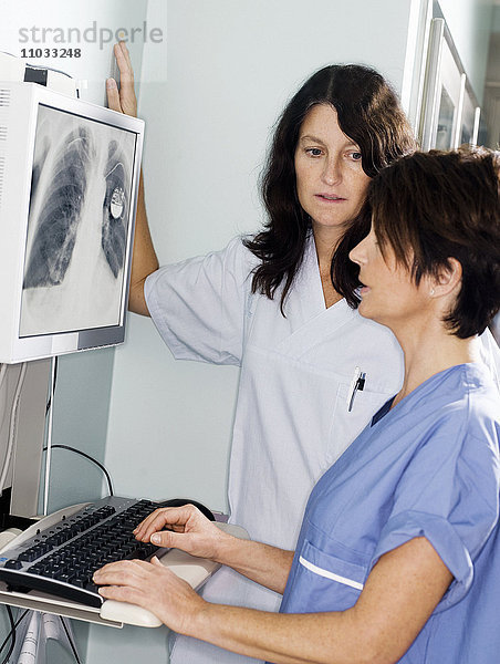 Ein Arzt und eine Krankenschwester sehen sich ein Röntgenbild an.