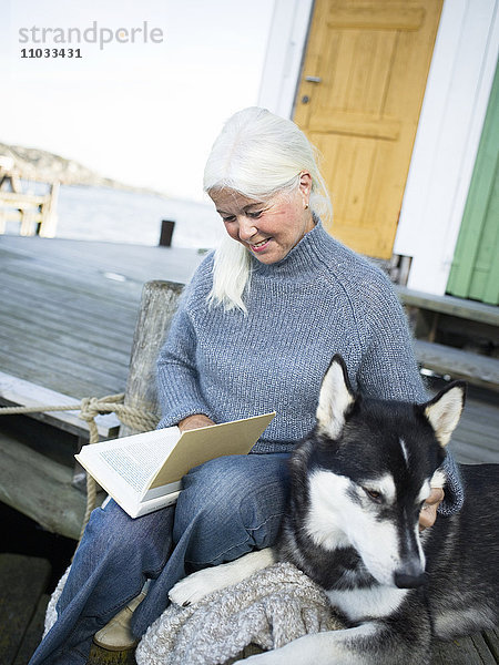 Eine Frau liest mit ihrem Hund ein Buch.