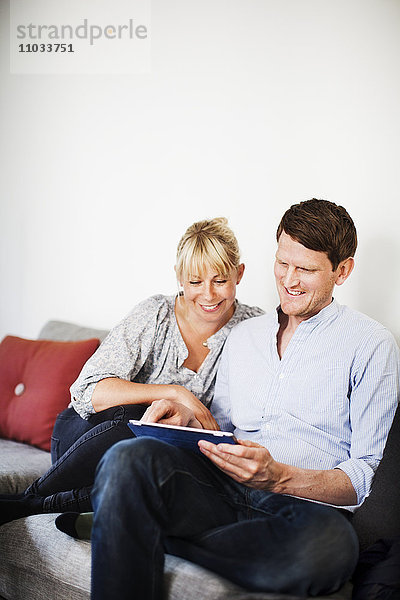 Ein Paar sitzt auf einem Sofa mit einem Tablet