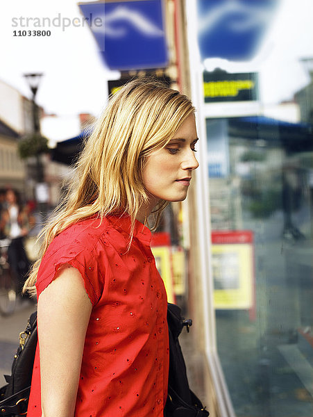 Eine junge Frau  die durch ein Schaufenster schaut.