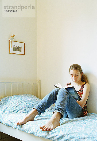 Ein junges Mädchen liest in ihrem Bett.