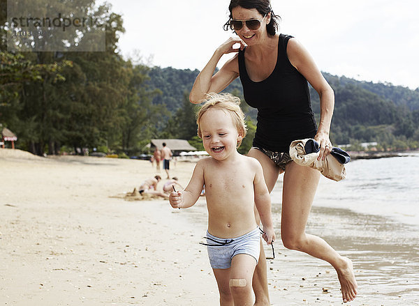 Mutter läuft mit Sohn am Strand