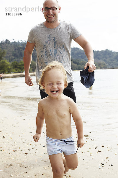 Vater läuft mit Sohn am Strand