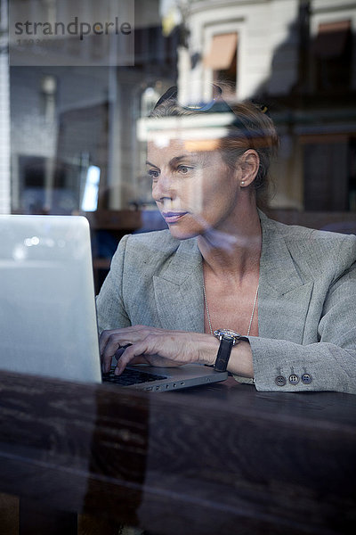Geschäftsfrau sitzt in einem Café und benutzt einen Laptop