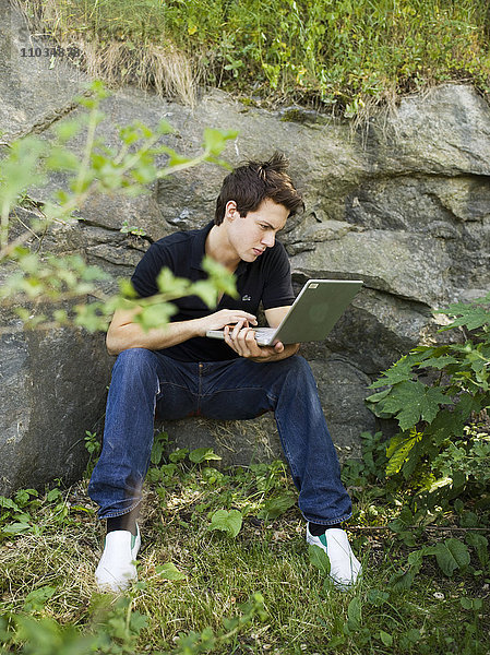 Ein Jugendlicher mit einem Computer im Freien  Schweden.