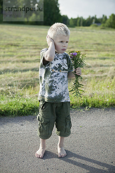 Junge hält Wildblumenstrauß auf der Straße