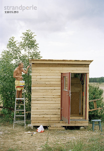 Ein Mann streicht eine Hütte.