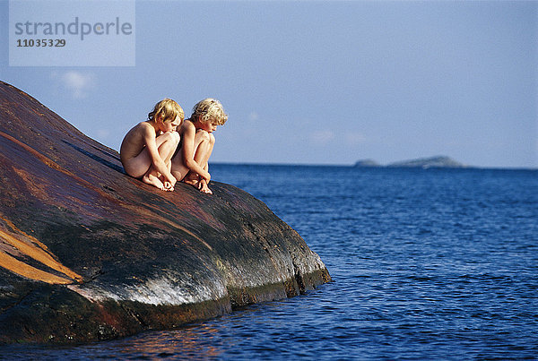 Jungen sitzen auf den Klippen am Meer  Schweden.