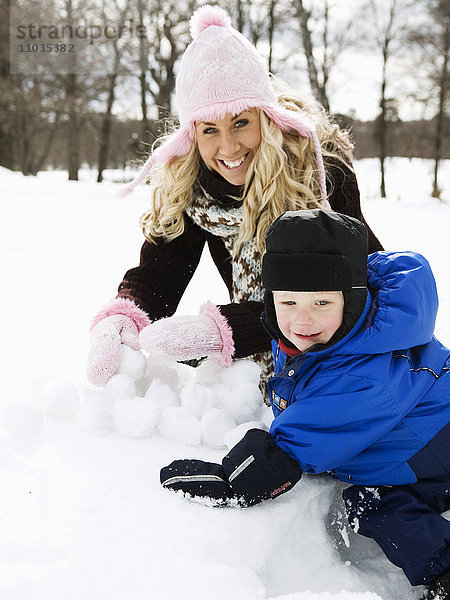 Eine Frau und ein Junge bauen eine Schneeball-Laterne.