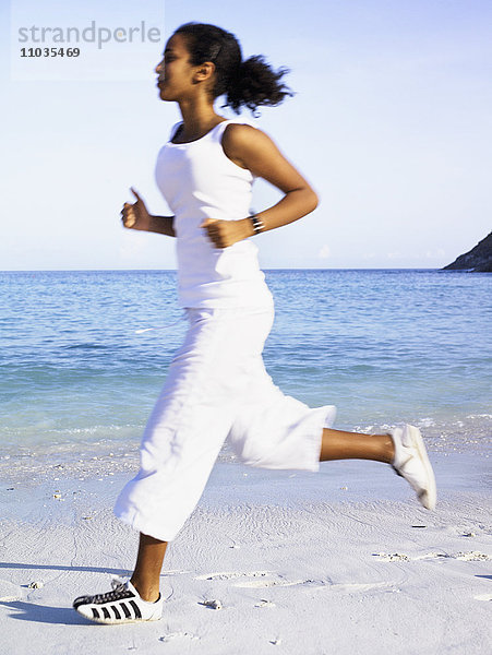 Eine Frau joggt am Strand.