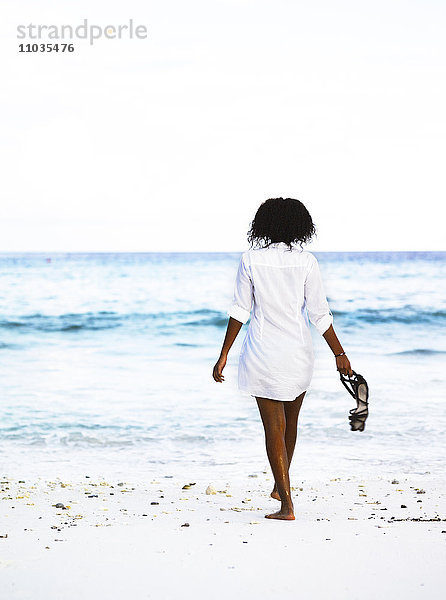 Eine Frau  die an einem Strand spazieren geht.
