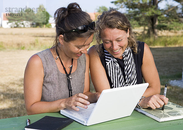 Zwei Frauen arbeiten gemeinsam an einem Laptop.