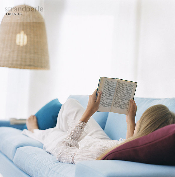 Frau auf Sofa  die ein Buch liest