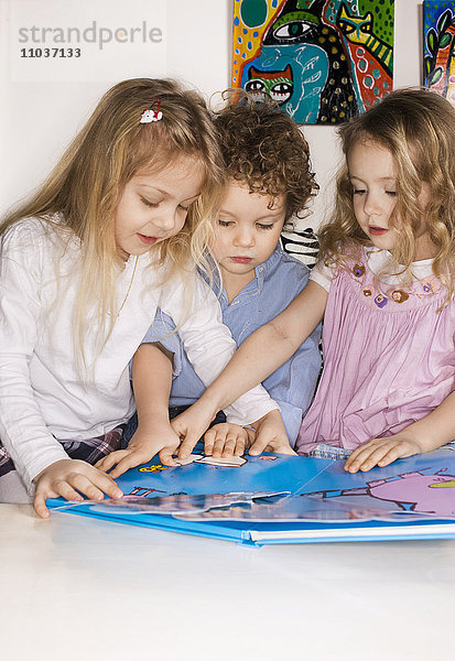 Drei Kinder mit einem Bilderbuch  Schweden.