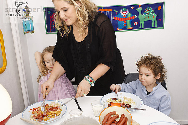 Mutter hilft ihren Kindern beim Abendessen  Schweden.