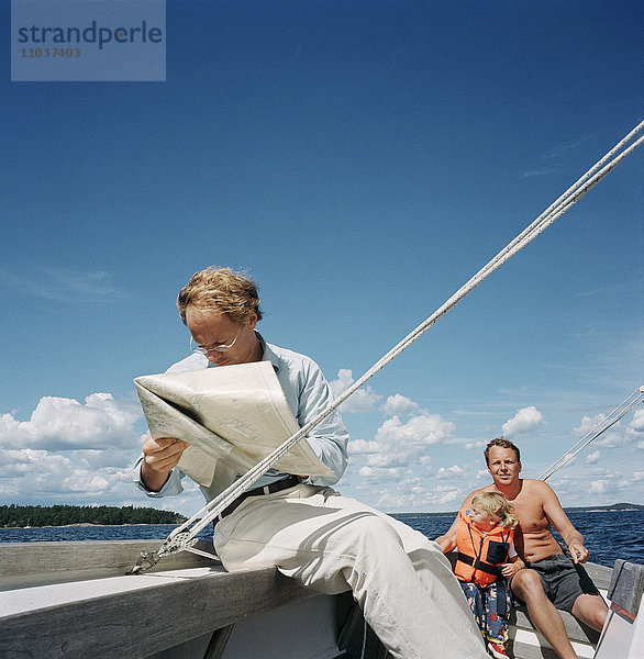 Zwei Männer und ein Kind beim Segeln  Schweden.