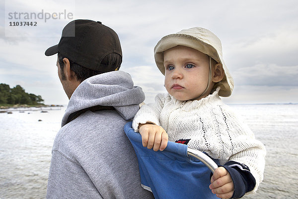 Kleinkind in einer Babytrage auf dem Rücken seines Vaters  Schweden.