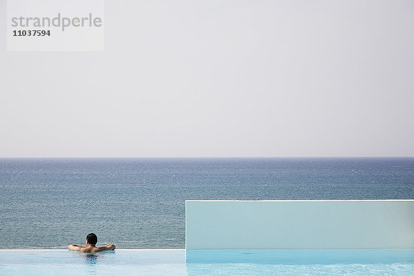 Mann in einem Schwimmbad mit Blick auf das Meer  Griechenland.