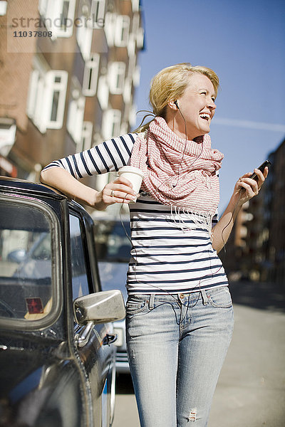 Frau benutzt ein Mobiltelefon neben einem Auto  Schweden.