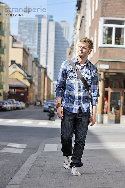 Junger Mann geht auf einer Straße  Schweden.