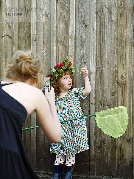 Kind mit einem Blumenkranz an einer Mauer  Schweden.