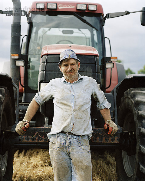 Ein Landwirt steht vor einem Traktor  Porträt.