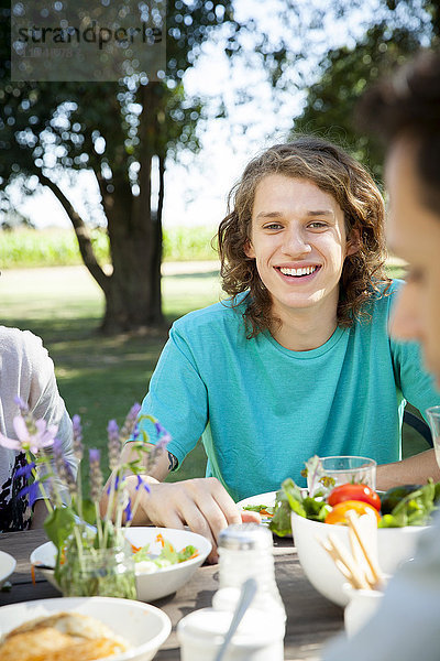 Junger Mann beim Essen mit Freunden im Freien