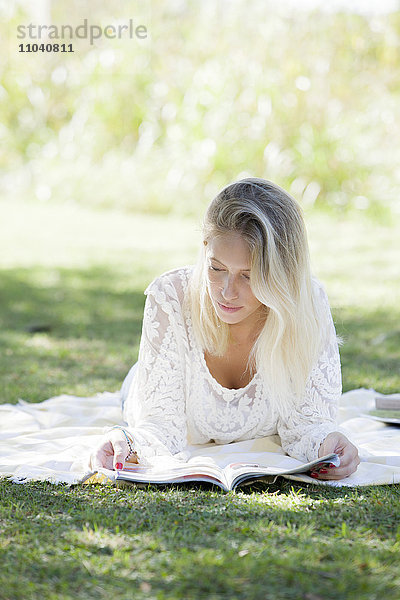 Frau liest Magazin im Park