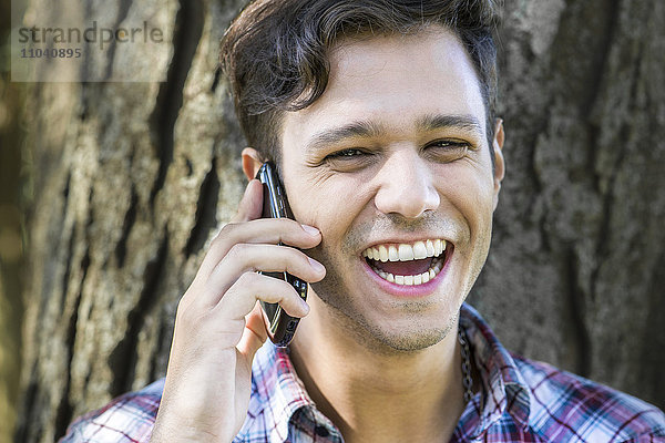 Mann mit fröhlichem Gespräch auf dem Handy