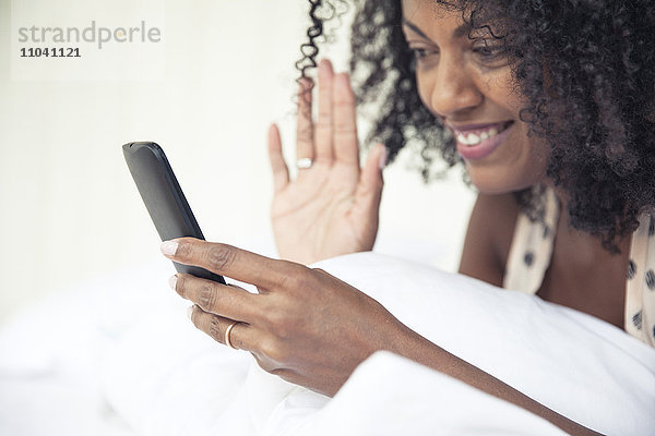 Frau winkt beim Videochat auf das Smartphone