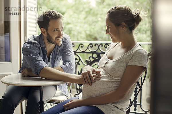 Mann ruht Hand auf dem schwangeren Magen seiner Frau.