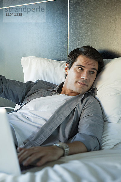 Mann entspannt im Bett mit Laptop-Computer