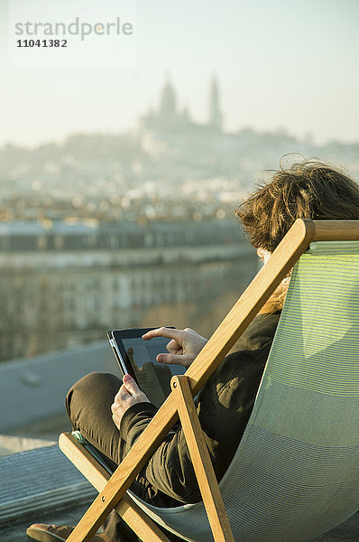 Mann mit digitalem Tablett auf der Dachterrasse