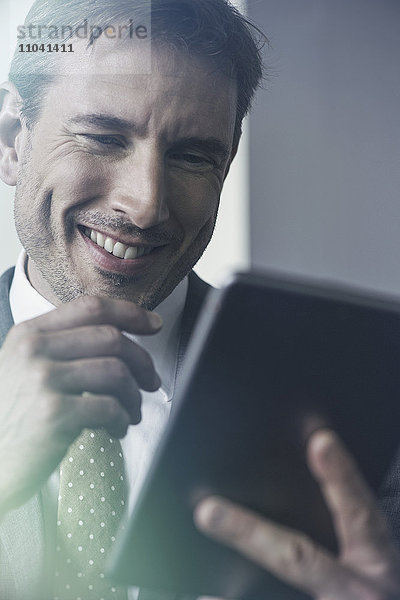 Geschäftsmann mit digitalem Tablett  fröhlich lächelnd
