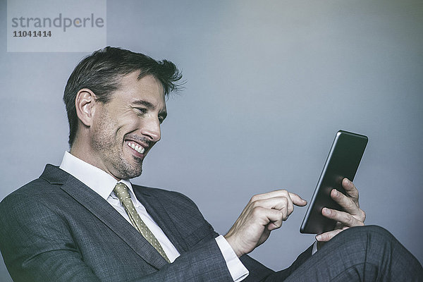 Der Mann lacht  während er ein digitales Tablett benutzt.