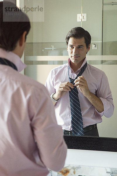 Mann stellt Krawatte im Badezimmerspiegel ein