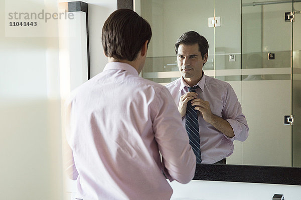 Mann schaut in den Badezimmerspiegel  verstellbare Krawatte