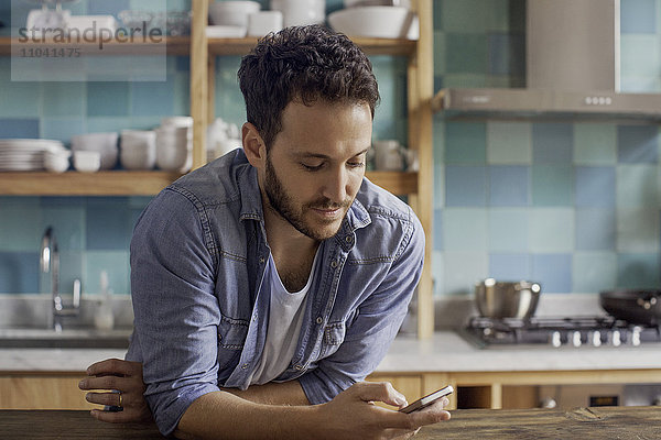 Mann zu Hause in der Küche Text-Messaging