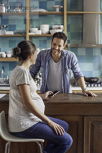 Schwangere Frau im Gespräch mit Mann in der Küche