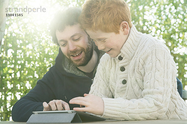 Vater und Sohn schauen gemeinsam auf das digitale Tablett