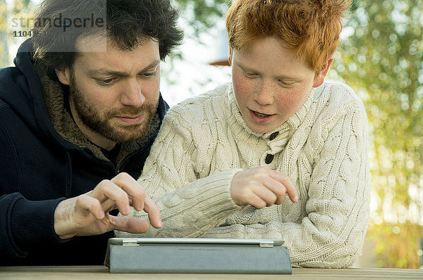 Vater und Sohn schauen gemeinsam auf das digitale Tablett